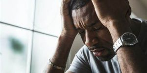 Man with a pained expression holding his head in distress, reflecting struggles with depression and mental health challenges.