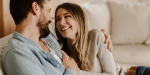 Couple smiling and embracing on a couch, representing healthy relationships and emotional connection in couples therapy.