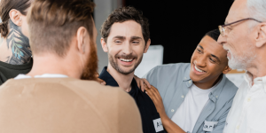Group of diverse men engaged in supportive conversation, emphasizing community and connection in substance use recovery.