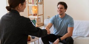 Man and woman shaking hands in a counseling session, symbolizing support in substance use and behavioral recovery.