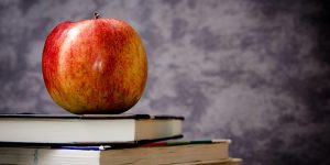 Apple resting on stacked books, symbolizing learning and knowledge in the context of anxiety management and coping strategies.