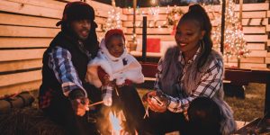 Family gathering around a cozy fire, enjoying a warm moment together, emphasizing connection and comfort during stressful times.