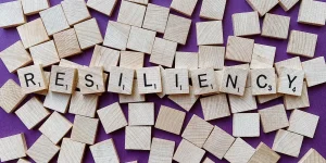 Wooden letter tiles spelling "RESILIENCY" surrounded by scattered tiles, symbolizing mental health themes and resilience in counseling.