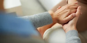 Hands of a counselor gently holding the hands of a client, symbolizing support and connection in substance use recovery.