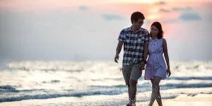 Couple walking hand in hand on the beach at sunset, symbolizing connection and intimacy in relationships.