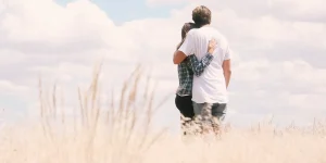 Couple embracing in a field, symbolizing support and connection, relevant to mental health and relationships in the context of depression.